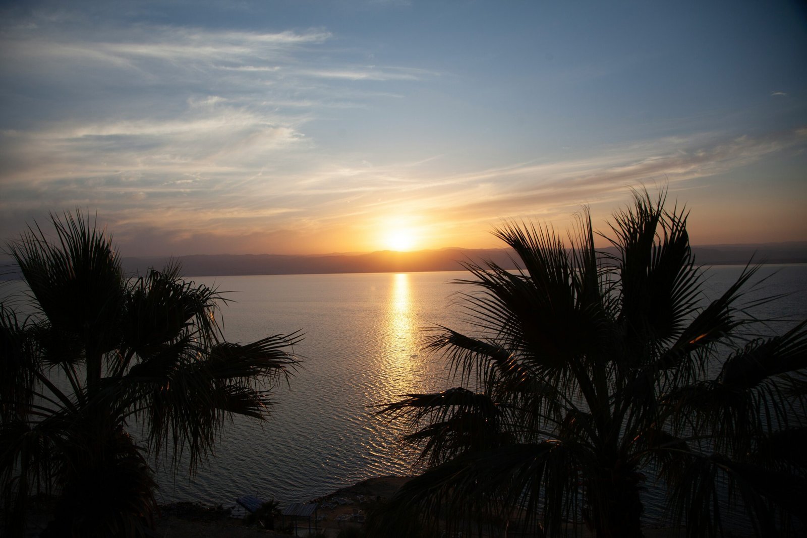 a sunset over a body of water with palm trees